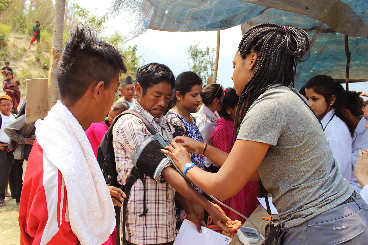 An intern taking blood pressure of patients gaining work experience during her nursing internship in Nepal. Female intern is pictured taking blood pressure of local during her nursing internship in Nepal with Projects Abroad.